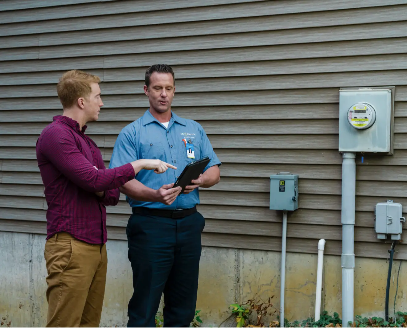 Homeowner and electrician reviewing electrical inspection results outdoors