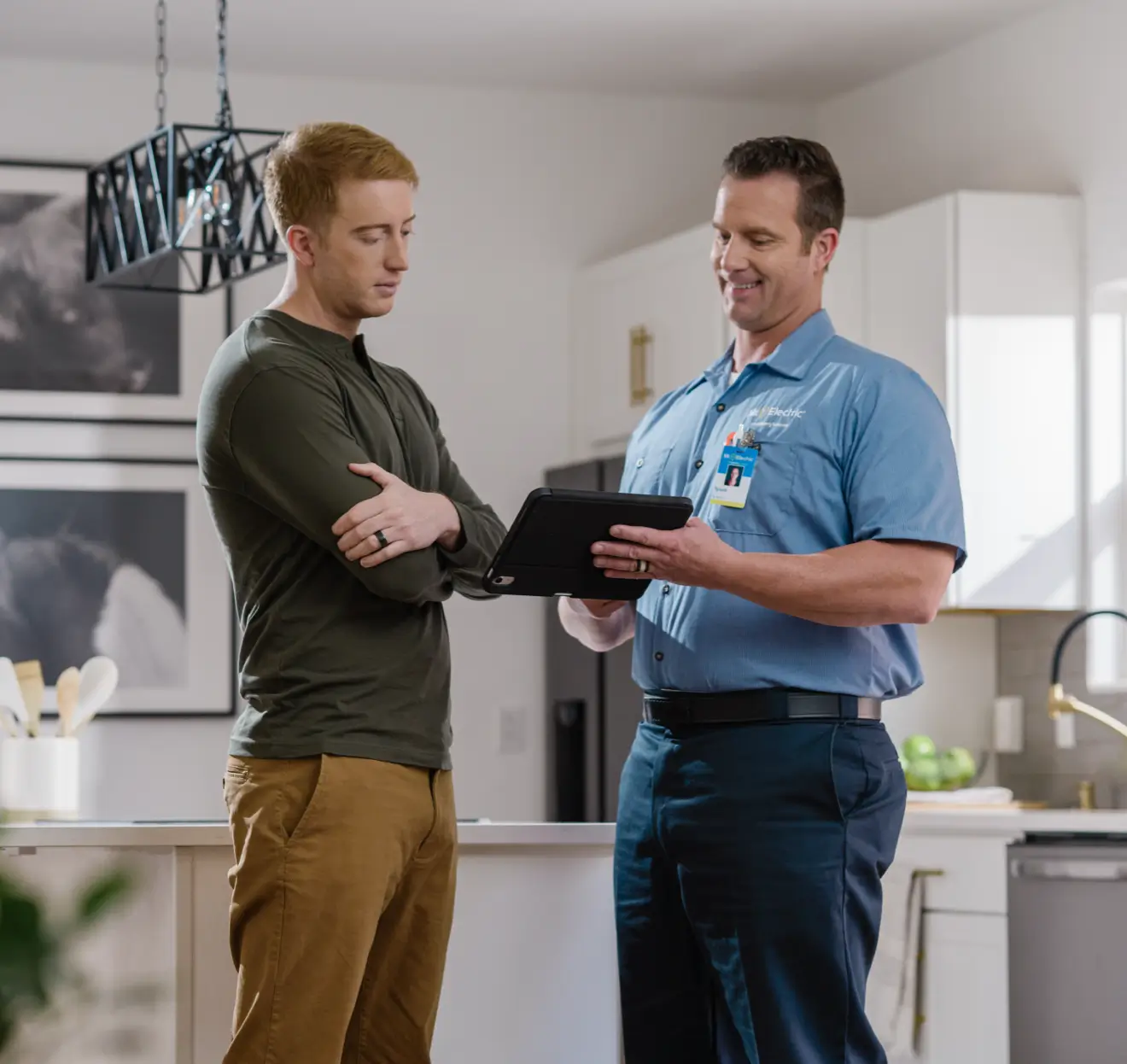 Electrician reviewing 240v outlet installation with homeowner in kitchen