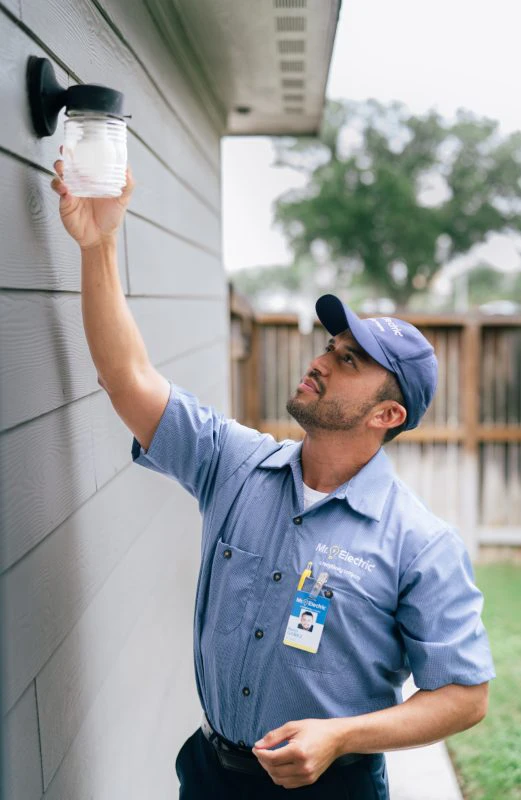 An electrician installing an outdoor light.