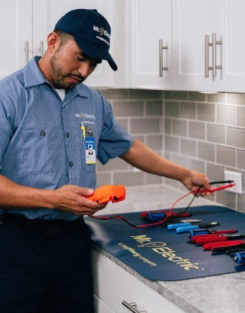 Mr. Electric electrician testing outlet voltage.